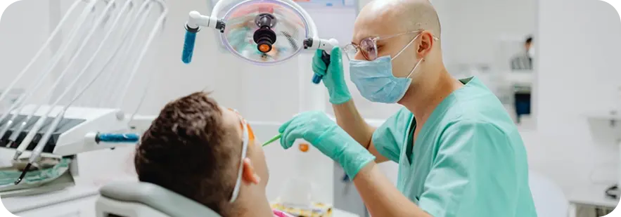 A man sits in a dental chair with a mask on